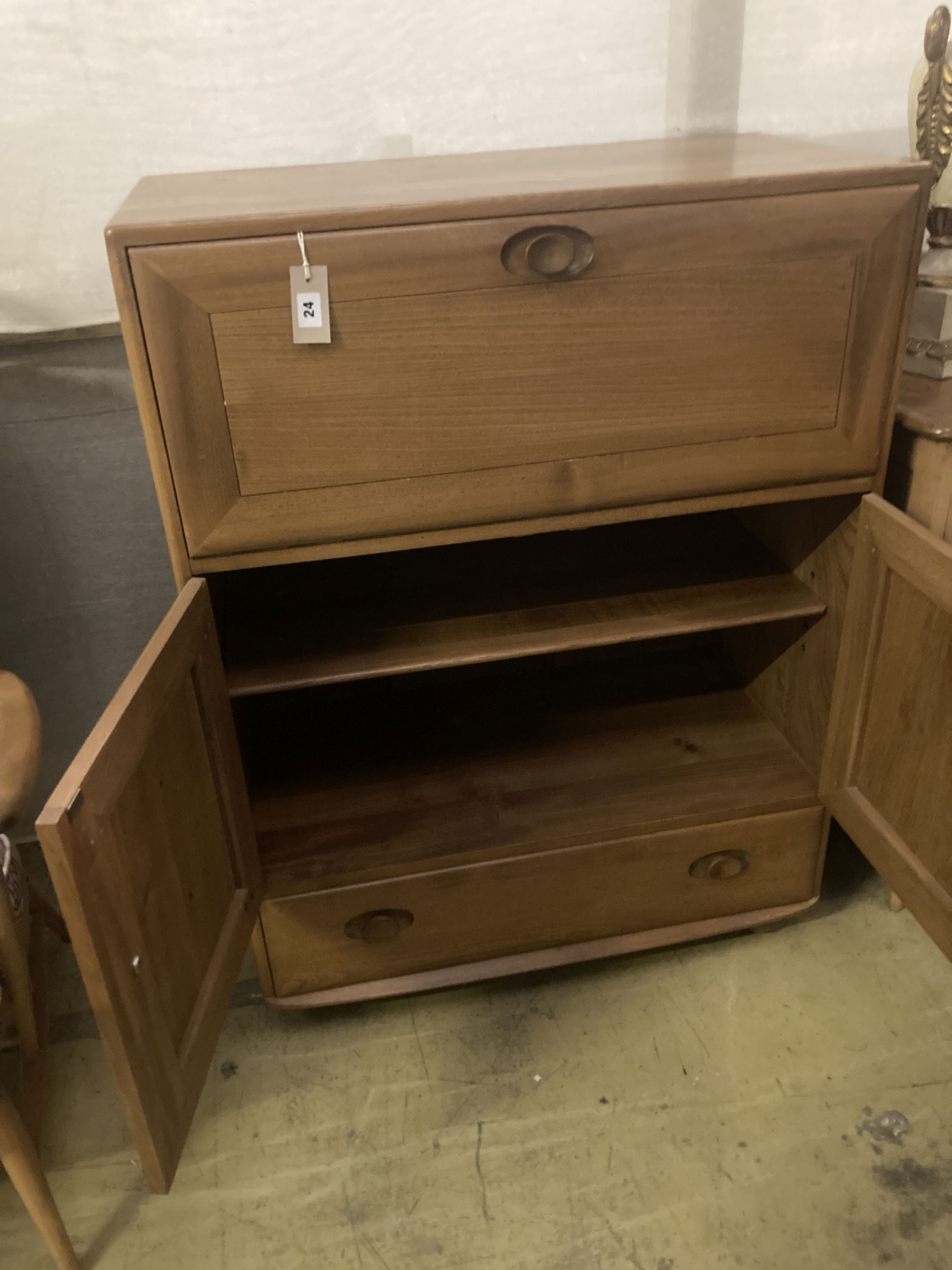 An Ercol elm drinks cabinet, fitted fall flap over cupboards and drawer, width 82cm depth 44cm height 110cm